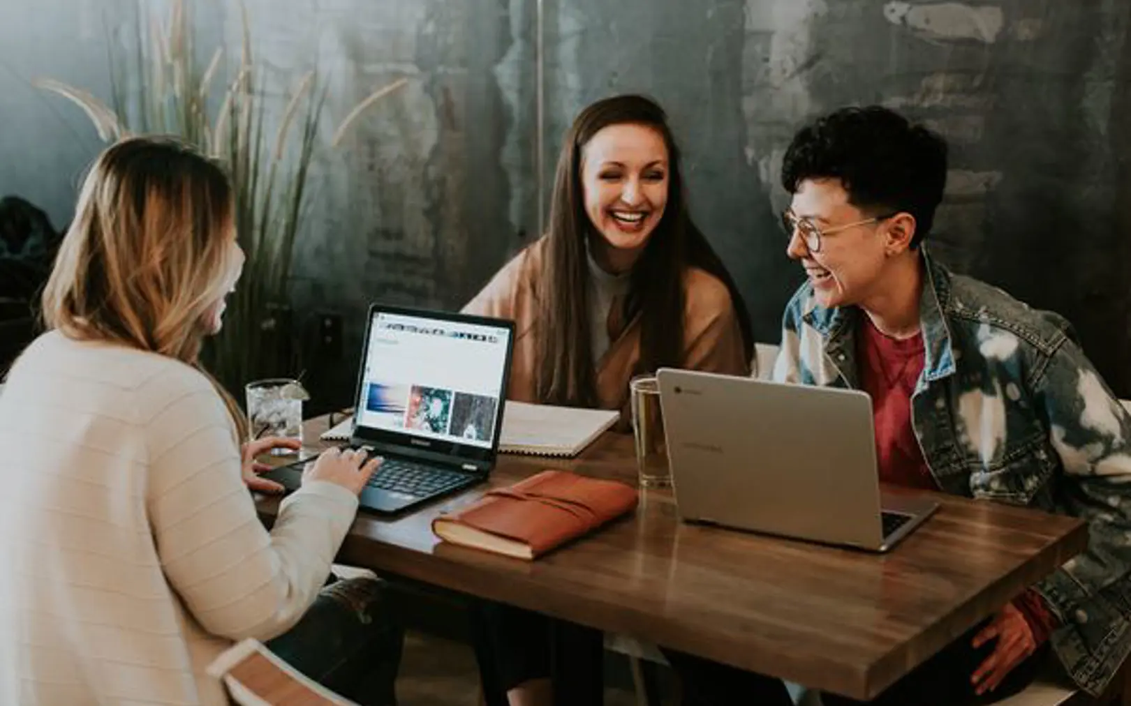 People at a table laughing around laptops.